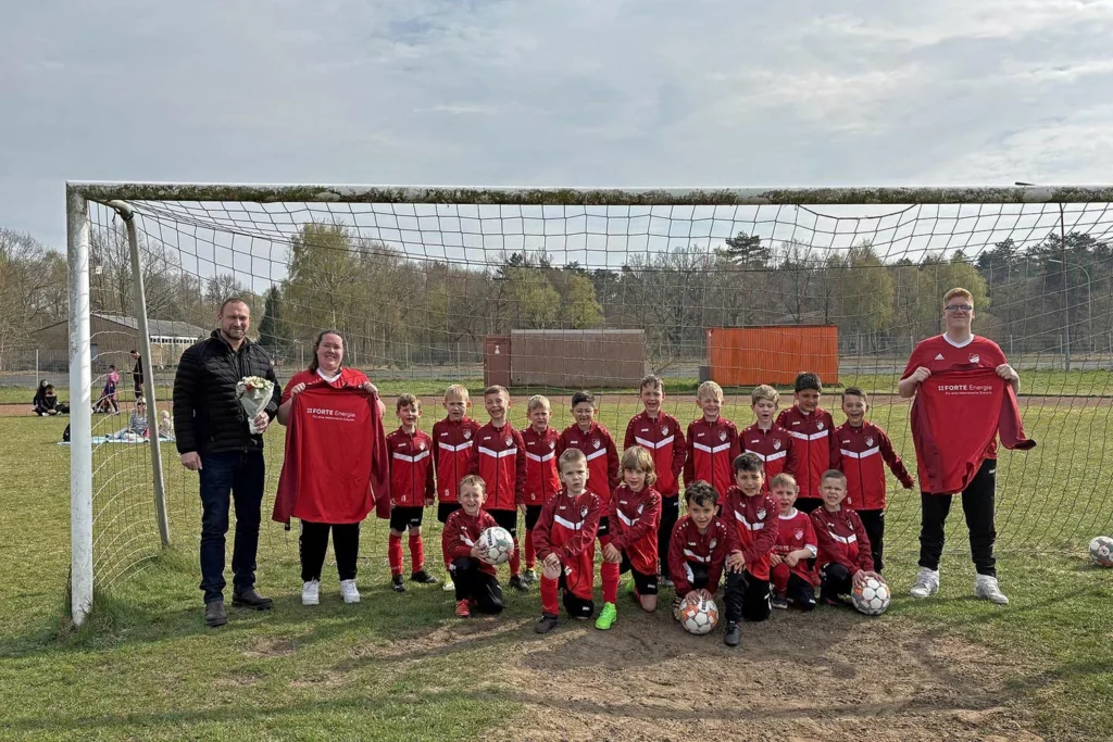 Lisa-Marie Mavroidakis und Leon Lobb vom TSV Altenwalde präsentieren gemeinsam mit ihren Schützlingen und Dr. Thomas Kalkau, dem Geschäftsführer der Forte Energie, die neue Mannschaftsbekleidung für die U7 I und II.